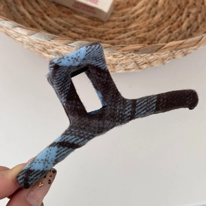Detailed close-up of blue and brown plaid fabric texture on a square hair claw clip