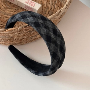 Close-up of a vintage grey plaid sponge headband next to a woven basket and incense sticks