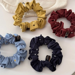 Dettaglio set di quattro elastici per capelli a pois in giallo, rosso, blu e navy