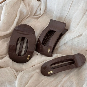 Trois pinces à cheveux élégantes texture marbre brun sur fond de tissu beige doux
