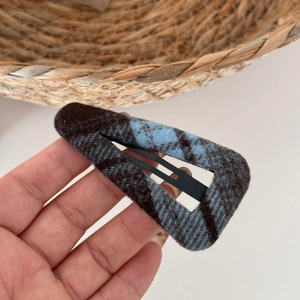 Detailed view of blue and brown checkered wool fabric hair clip with a drop shape