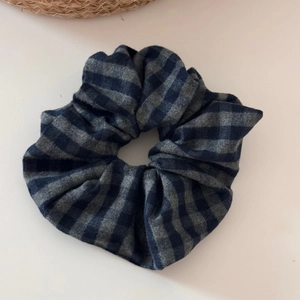 Detailed view of the dark blue and grey checkered fabric scrunchie with soft texture