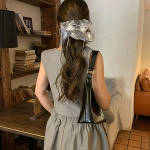Détail du grand nœud papillon en satin argenté avec rubans sur cheveux ondulés
