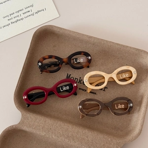 Detail of four colorful acetate hair clips with crystal accents in a brown eco tray