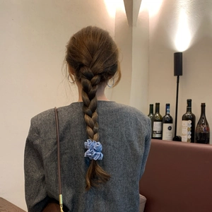 Elastico per capelli a pois azzurro in tessuto mostrato sulla coda di cavallo intrecciata