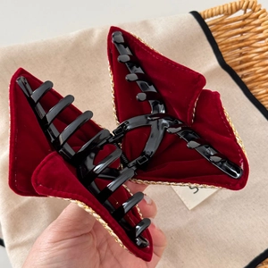 Macro shot of large burgundy velvet hair claw clip with detailed gold woven lace trim