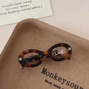 Detail of tortoise shell acetate hair clip in retro oval sunglass design with Like text