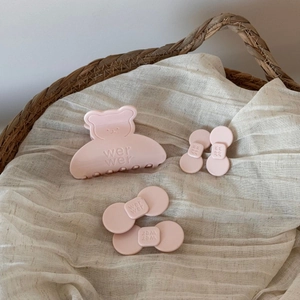 Haarklammer-Set mit Bärenmotiv in Rosa auf Leinenstoff in einem geflochtenen Korb
