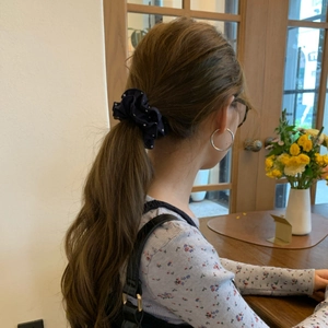 Dettaglio di un elastico per capelli blu a pois con grandi orecchini a cerchio