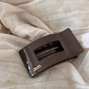 Détail d'une grande pince à cheveux rectangulaire marron foncé avec lettrage doré