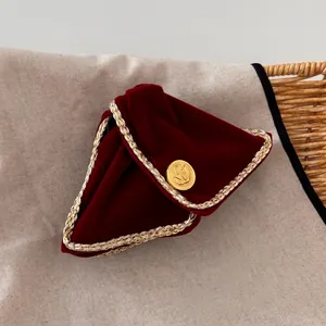 Detail view of burgundy velvet material with gold braided trim and a gold embossed button