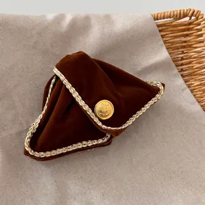 Detail of a brown velvet triangle pouch with a gold vintage button and woven trim border