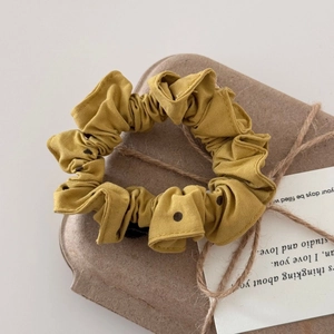 Dettaglio di scrunchie giallo senape a pois su confezione regalo in carta kraft vintage
