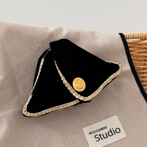 Close-up of black velvet headband with gold braided edges and vintage embossed button