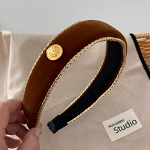 Close-up of retro brown velvet headband with gold braided edges and metal button
