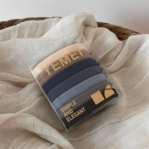 Set of high-elasticity hair ties in neutral tones stored in a clear branded gift box