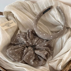 Close-up of handmade brown fabric headband and scrunchie set with white bow patterns