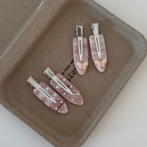 Détail de barrettes en acétate avec strass roses et nœuds décoratifs dans un plateau