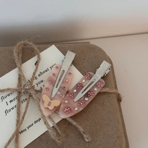 Détail de barrettes en résine marbrée rose avec strass sur un coffret cadeau