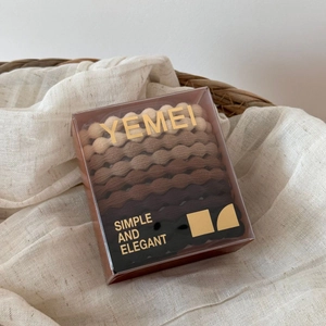 Close-up of high-elasticity wavy hair ties in gradient earth tones in a clear box