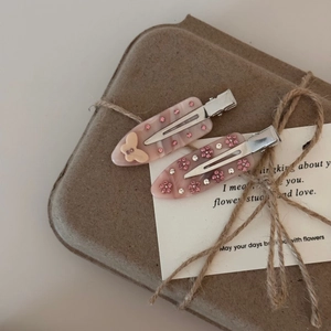 Détail de barrettes en acétate rose avec strass papillon sur boîte en papier kraft