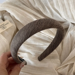 Detail of a brown ribbed fabric headband showing its textured surface and non-slip lining