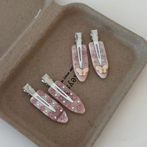 Vue détaillée des barrettes en acétate rose marbré avec strass et motifs floraux