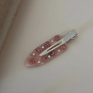 Détail de la pince à cheveux en acétate marbré rose avec motif floral en strass brillant