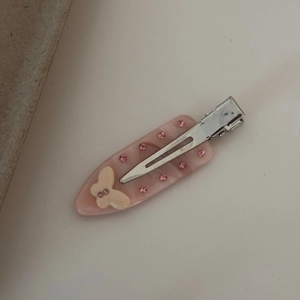 Vue détaillée d'une pince à cheveux en acétate rose avec strass et motif papillon