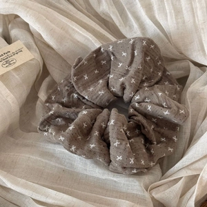 Close-up of brown cotton fabric scrunchie with white bow and polka dot patterns