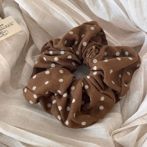 Close-up of brown polka dot fabric scrunchie with corduroy texture on linen cloth