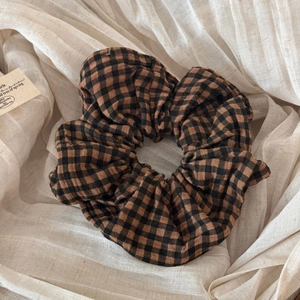 Detailed shot of brown gingham fabric hair tie texture on soft beige background
