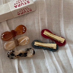 Detailed close-up of acetate bow hair clips with marble patterns and rhinestones