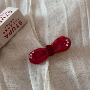 Detail shot of a pearlescent deep red bow hair clip with sparkling rhinestone accents