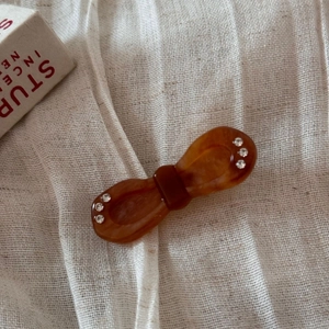 Close-up of tortoise shell bow hair clip with sparkling rhinestones on beige fabric