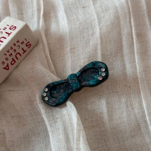 Detail of a marble textured acetate bow hair clip with small rhinestones on white linen