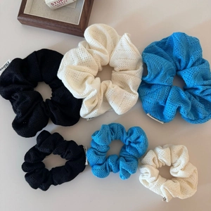 Vue détaillée de six chouchous tricotés en noir, blanc et bleu avec une texture douce