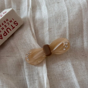 Detail of acetate bow hair clip with brown marble texture and sparkling rhinestones