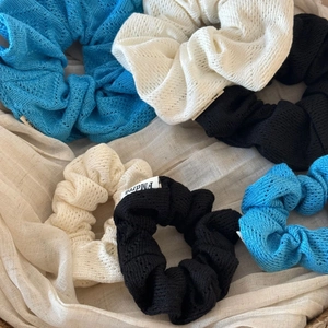Chouchous en tricot ajouré en bleu, blanc et noir posés sur un tissu neutre doux