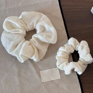 Détail de deux chouchous en tricot blanc cassé avec textures florales ajourées complexes