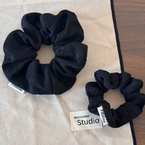 Détail de chouchous en maille noire de deux tailles montrant la texture et l'étiquette