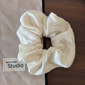 Gros plan détaillé d'un chouchou en maille crème montrant la texture au crochet et l'élasticité