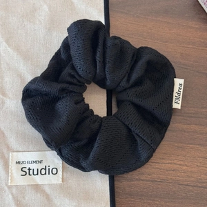 Vue détaillée du chouchou en maille noire avec une étiquette de marque blanche