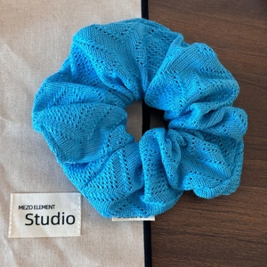 Détail de la texture tricotée du chouchou crochet bleu clair au design ondulé élastique