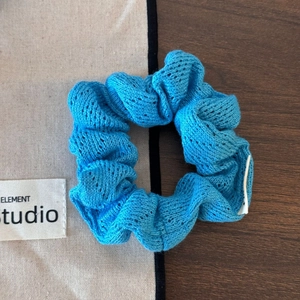 Détail macro du chouchou en tricot bleu roi montrant la texture ajourée du crochet