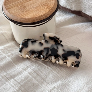 Detail of large marble pattern acetate hair claw clip on white fabric background