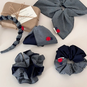 Détail de la pince à cheveux en tissu écossais bleu marine avec boutons rouges et bleus