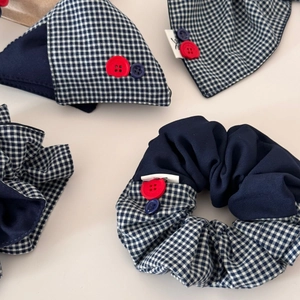 Détail de la pince à cheveux en tissu vichy marine avec boutons rouges et bleus décoratifs