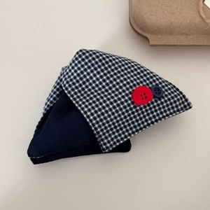 Détail de la pince à cheveux à carreaux bleu marine avec boutons rouges décoratifs