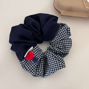 Détail d'un chouchou en tissu à carreaux bleu marine avec boutons décoratifs gravés